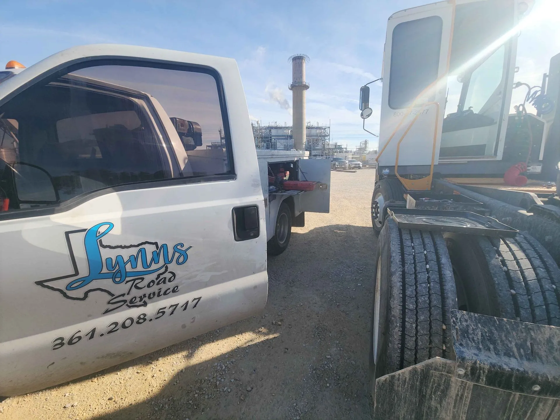 White truck with Lynn's Road Service logo next to a semi-truck in a dusty lot